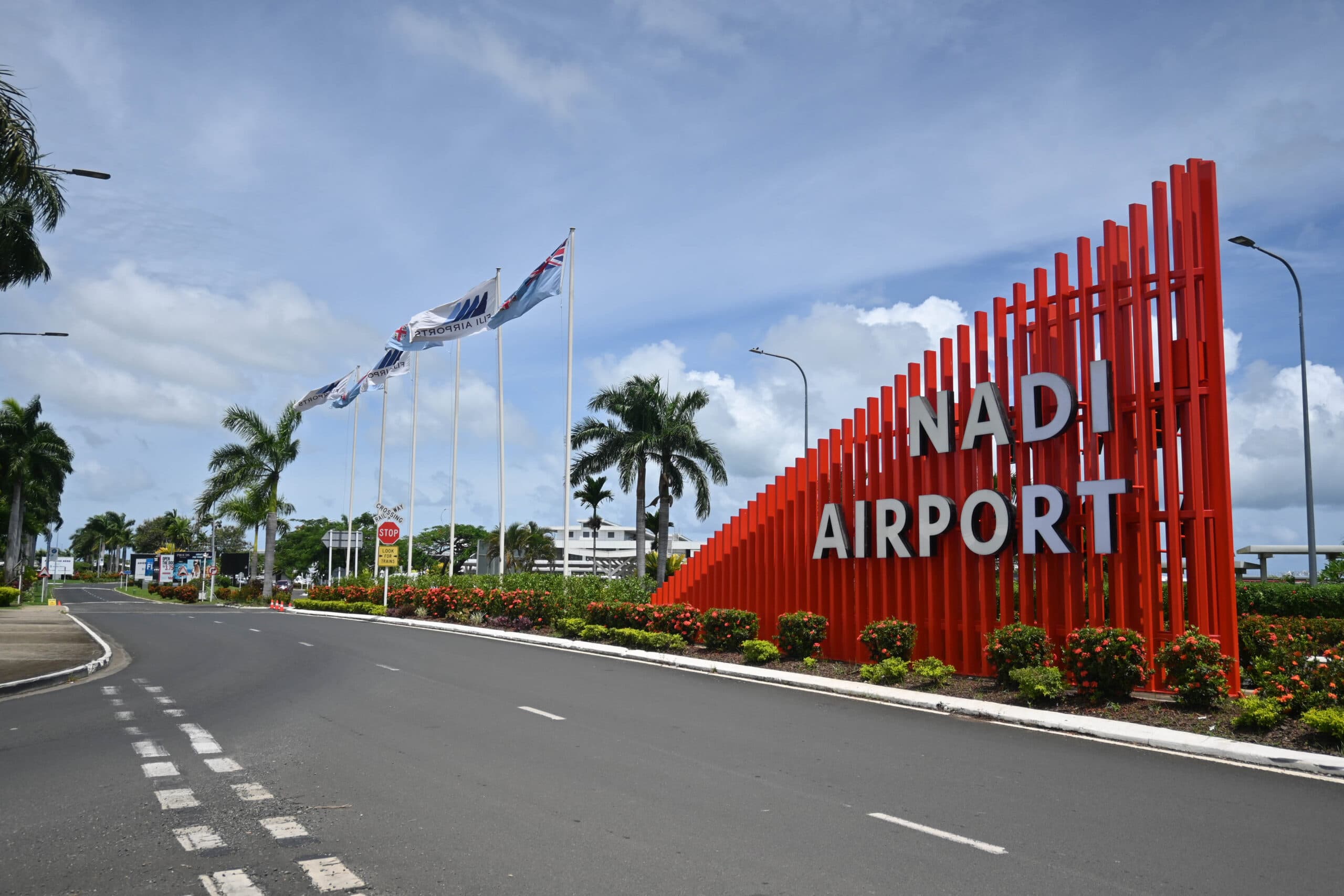 Nadi International Airport entrance sign with red NADI AIRPORT lettering and Fiji flags
